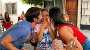 pais brincando de torta na cara e beijando a aniversariante